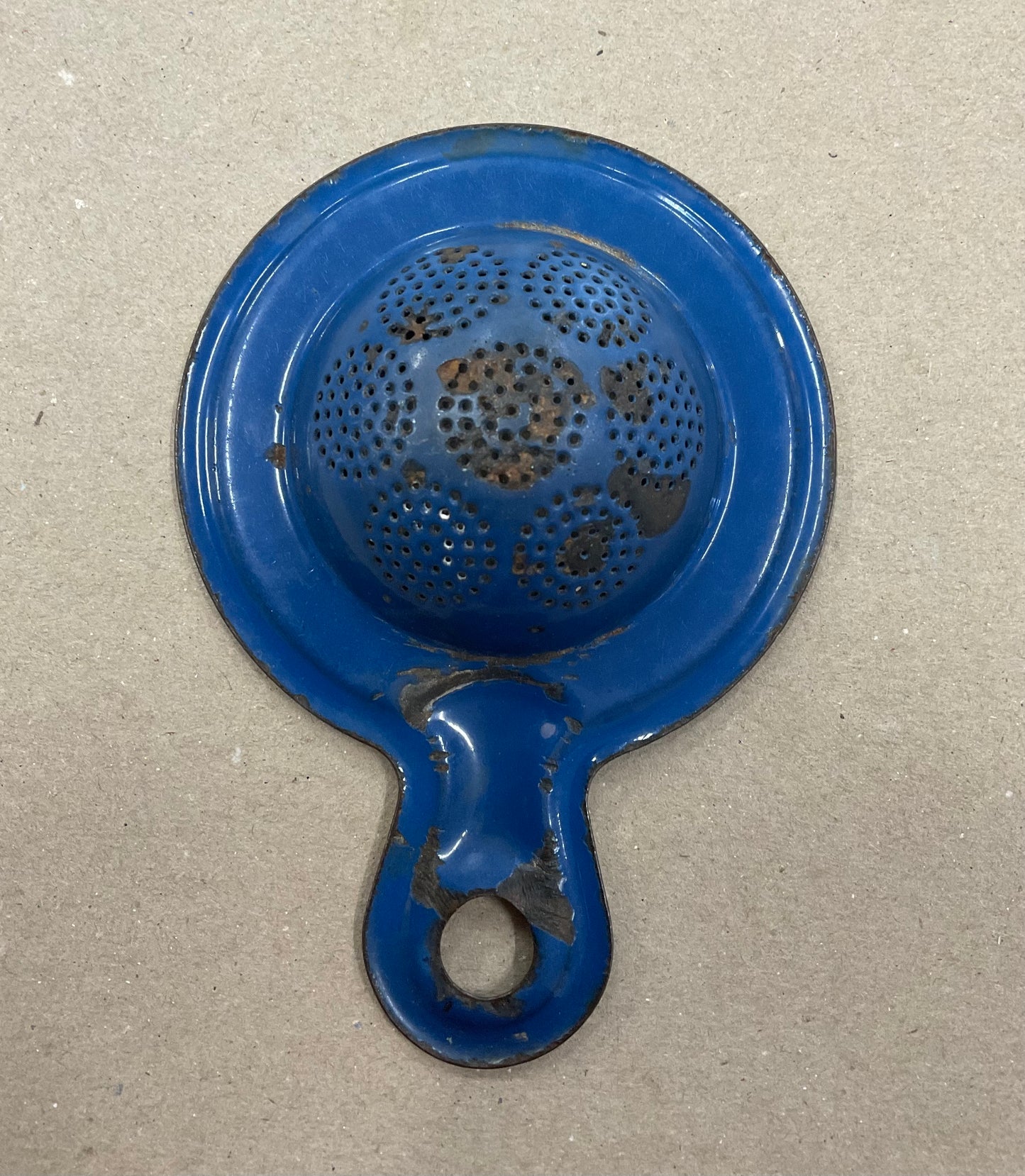 A vintage enamel tea strainer advertising Bushells Blue Label