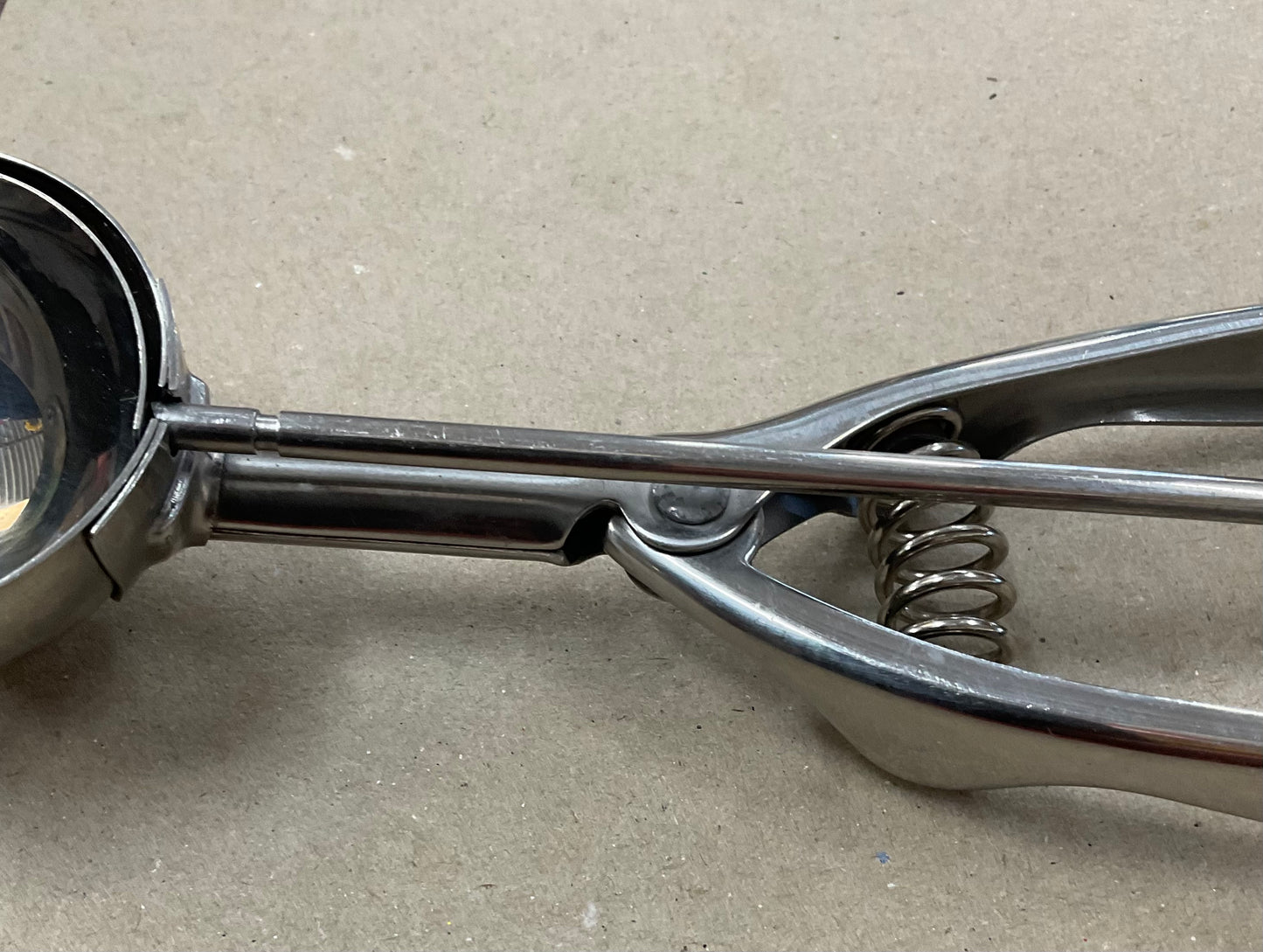 Vintage stainless steel ice cream scoop with spring-loaded handle and scraper mechanism