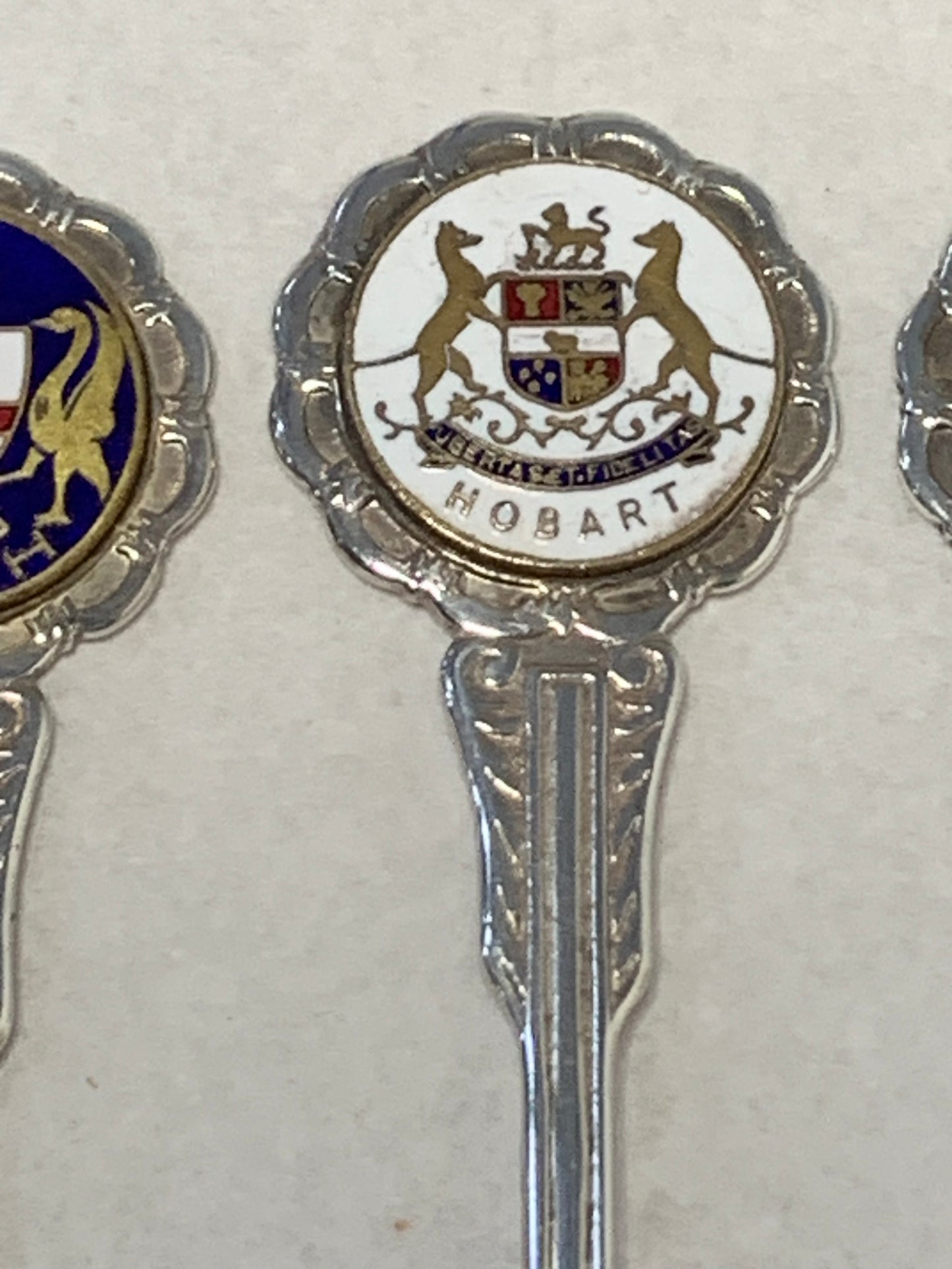Set of six vintage silver-plated souvenir teaspoons featuring the enameled coats of arms of Australia’s state capital cities: Adelaide, Brisbane, Sydney, Perth, Hobart, and Melbourne
