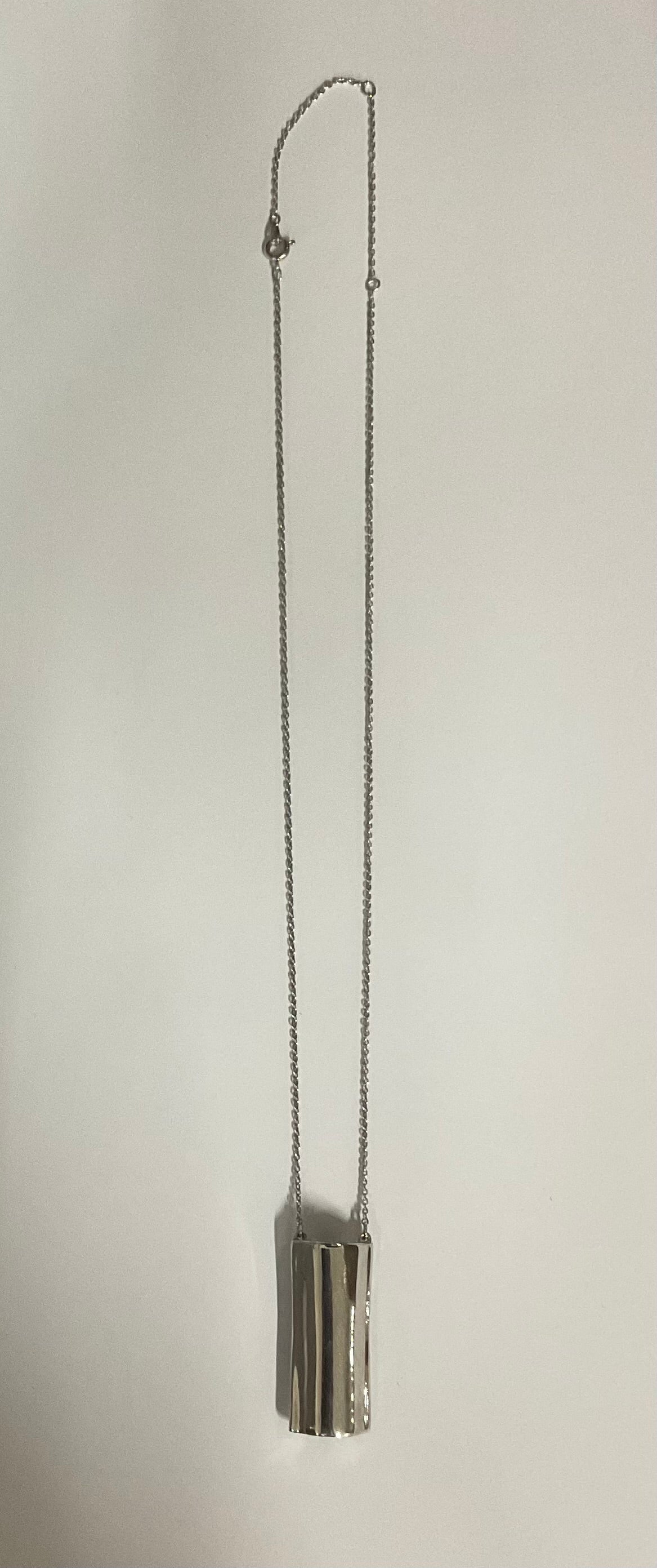 Vintage AVON modernist silver-tone pendant necklace featuring a sculptural tubular pendant with a reflective, wave-like design