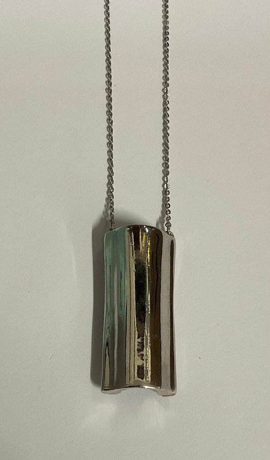 Vintage AVON modernist silver-tone pendant necklace featuring a sculptural tubular pendant with a reflective, wave-like design