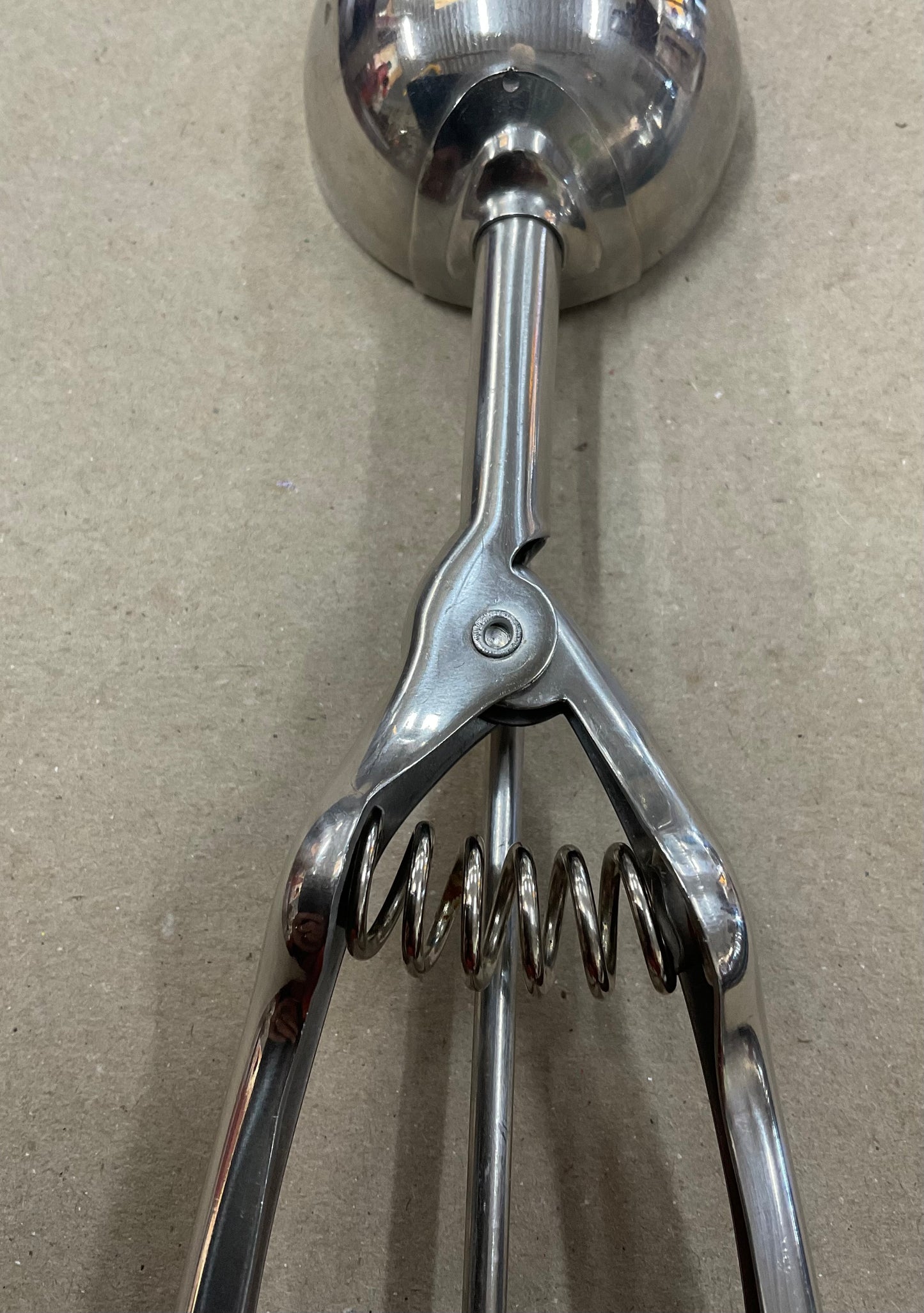Vintage stainless steel ice cream scoop with spring-loaded handle and scraper mechanism