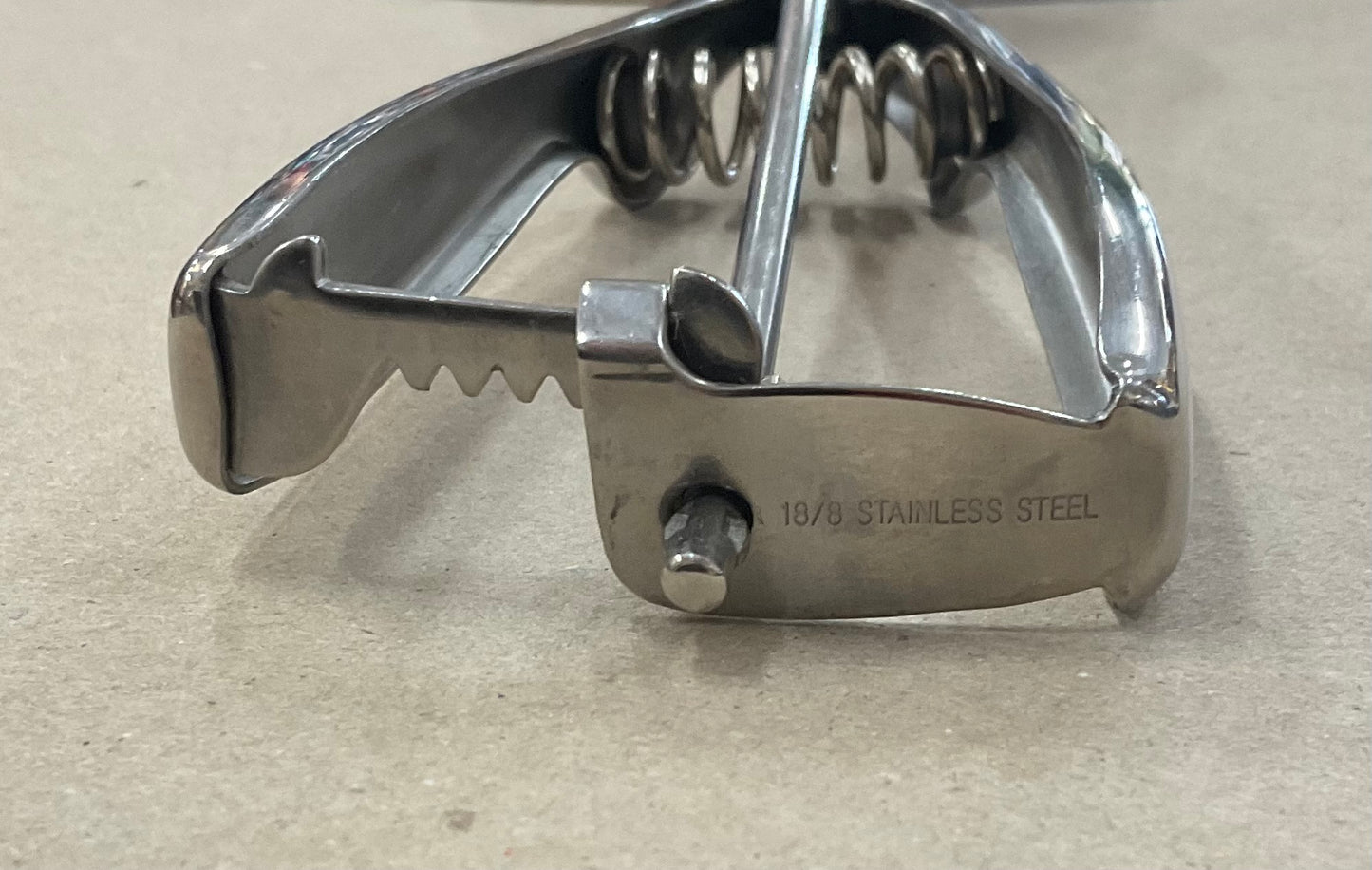 Vintage stainless steel ice cream scoop with spring-loaded handle and scraper mechanism