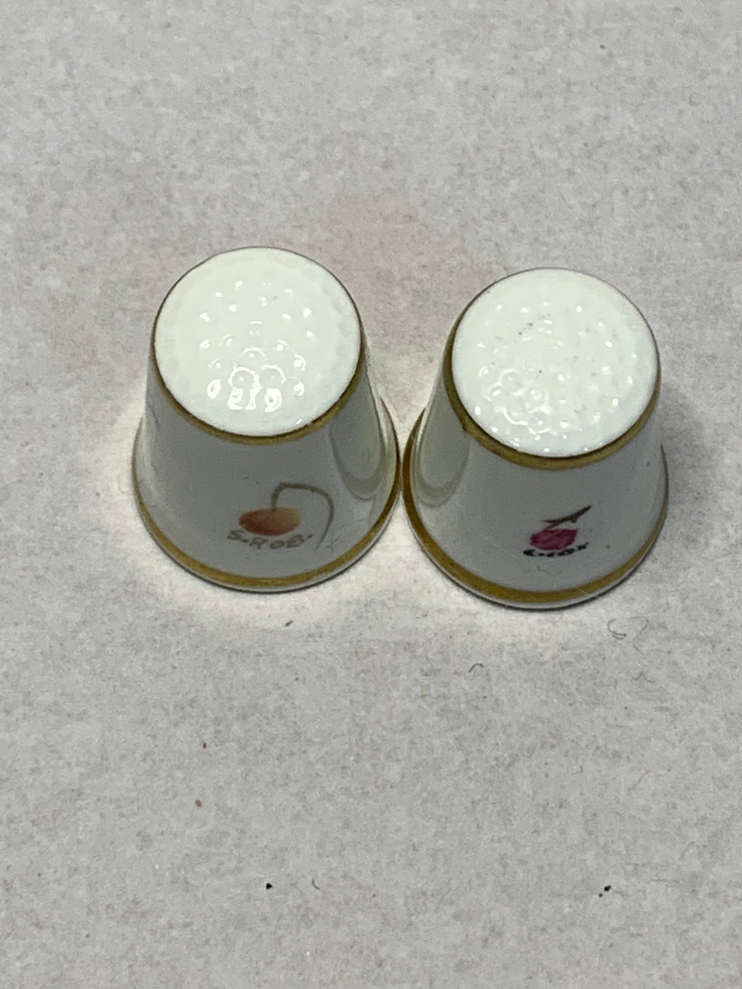 Pair of Royal Worcester fine bone china thimbles, hand-painted with fruit still-life designs (plums, cherries, apricots, and berries) on a white ground with gilt rims 1951